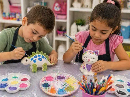 Dos niños pintando figuras de cerámica